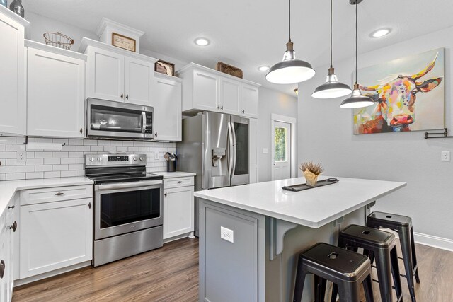 kitchen with white cabinetry, appliances with stainless steel finishes, a center island, and a breakfast bar