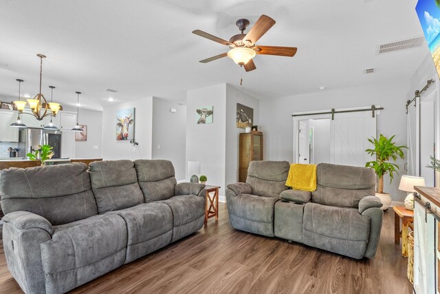 living room with wood-type flooring, a barn door, and ceiling fan