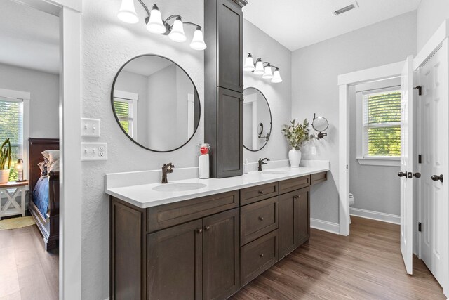 bathroom with hardwood / wood-style floors, a wealth of natural light, vanity, and toilet