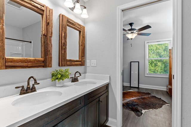 bathroom with walk in shower, vanity, hardwood / wood-style flooring, and ceiling fan