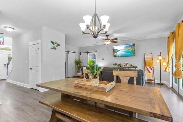 dining space featuring hardwood / wood-style floors, a barn door, and ceiling fan