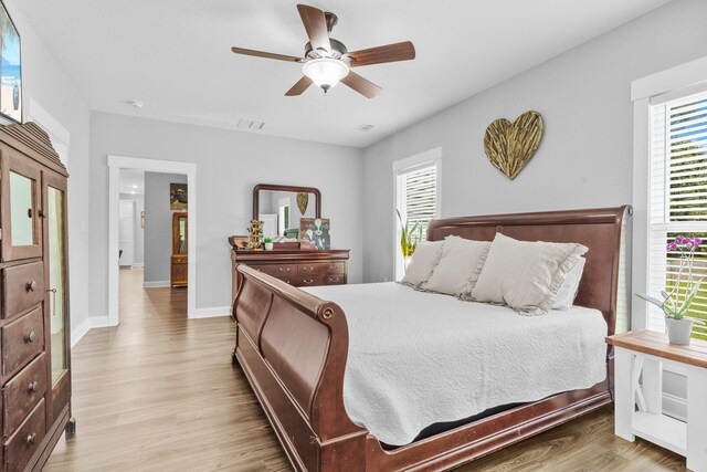 bedroom featuring multiple windows, wood-type flooring, and ceiling fan