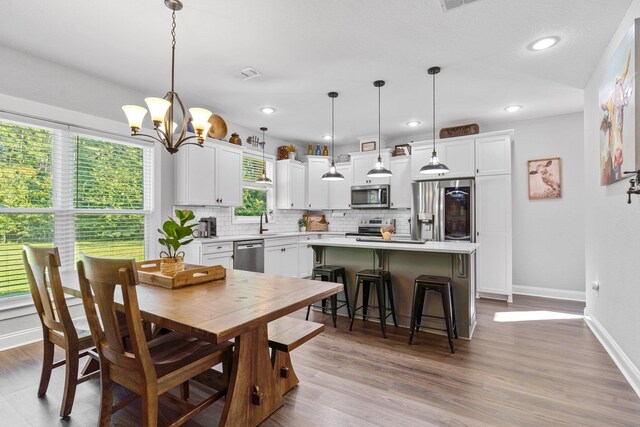 dining area featuring a chandelier, sink, and light wood-type flooring