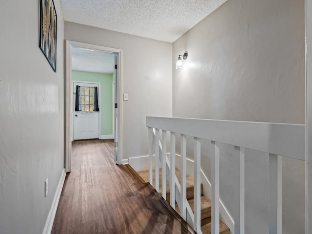 corridor with a textured ceiling and hardwood / wood-style flooring