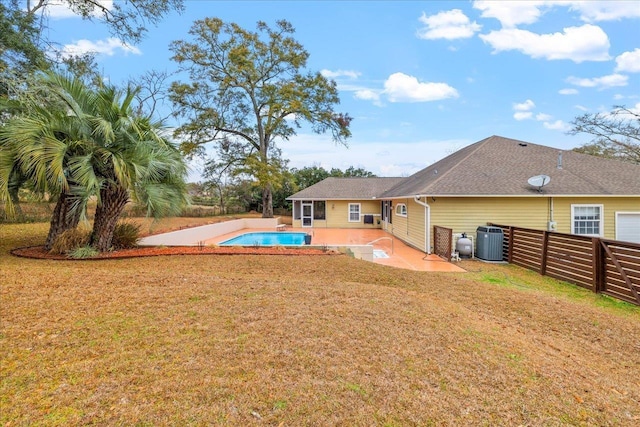 rear view of property featuring central AC unit, a patio, and a lawn