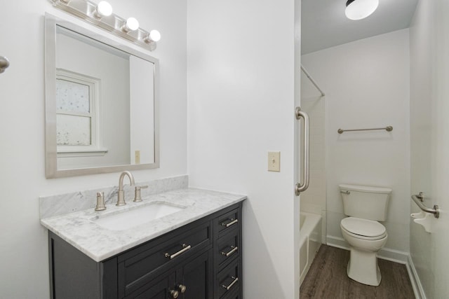 bathroom featuring toilet, wood finished floors, vanity, baseboards, and shower / bathing tub combination