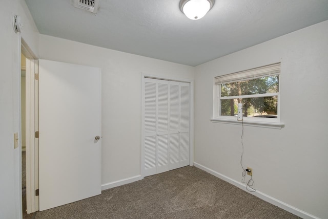 unfurnished bedroom featuring carpet floors, baseboards, visible vents, and a closet