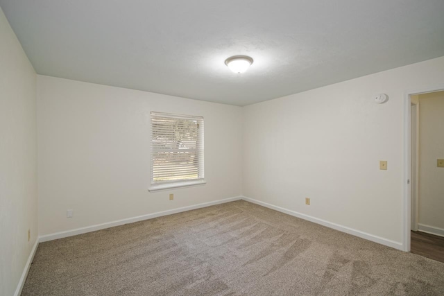 carpeted spare room featuring baseboards