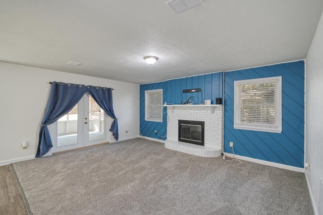 unfurnished living room featuring carpet floors, baseboards, a fireplace, and visible vents