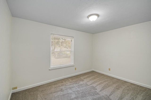 empty room featuring carpet and baseboards