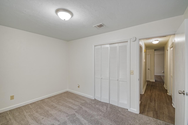 unfurnished bedroom featuring carpet floors, baseboards, visible vents, and a closet