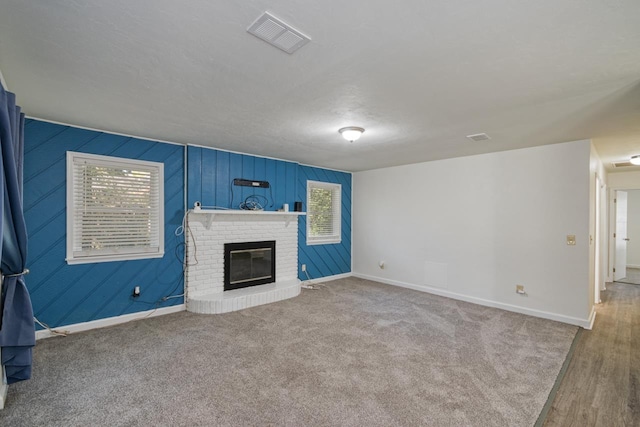 unfurnished living room featuring plenty of natural light, a fireplace, visible vents, and baseboards