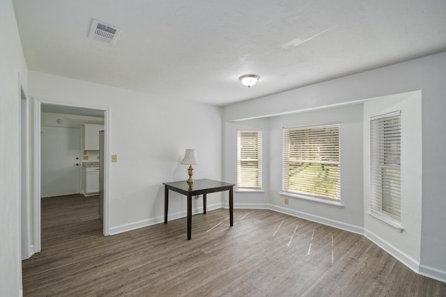 spare room featuring visible vents, baseboards, and wood finished floors