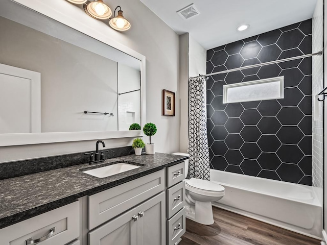 full bathroom with wood-type flooring, vanity, shower / bath combination with curtain, and toilet