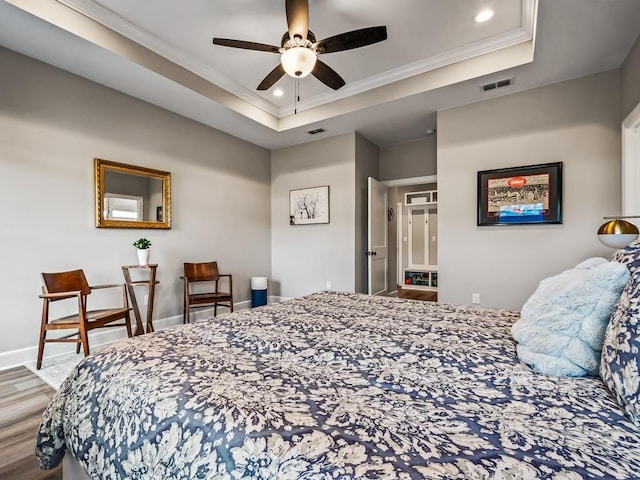 bedroom with a tray ceiling, ceiling fan, crown molding, and wood-type flooring