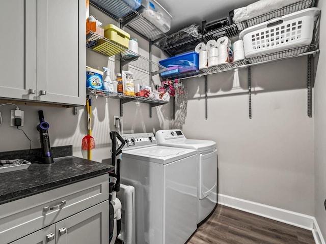 clothes washing area featuring washer and dryer, dark hardwood / wood-style floors, and cabinets