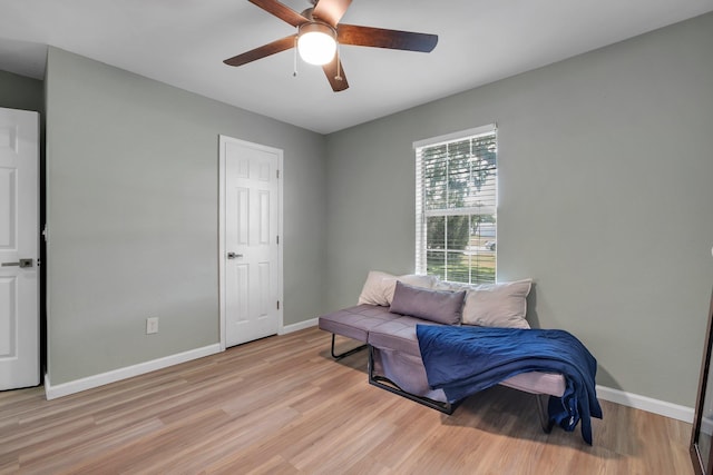 living area featuring light wood-style flooring, a ceiling fan, and baseboards