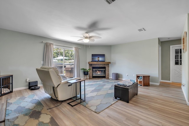 living area featuring a fireplace, wood finished floors, a ceiling fan, and baseboards