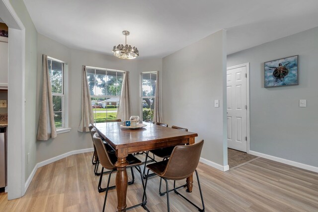 dining room with light wood finished floors, a chandelier, and baseboards