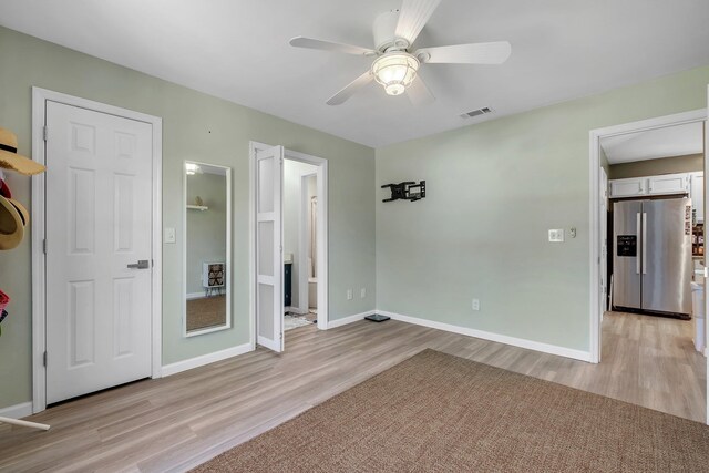 unfurnished bedroom with stainless steel fridge with ice dispenser, light wood-style floors, baseboards, and a ceiling fan