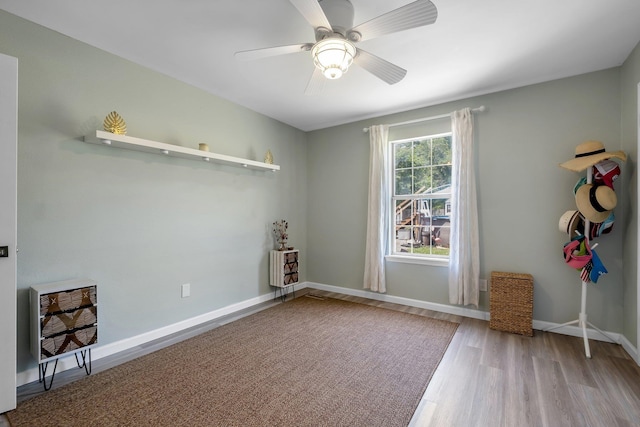 spare room featuring wood finished floors, ceiling fan, heating unit, and baseboards