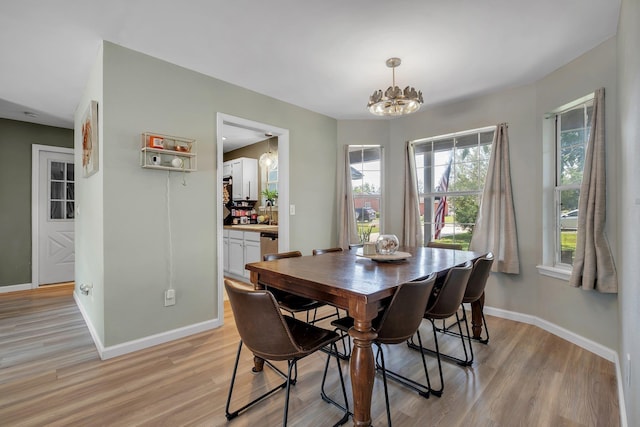dining room with light wood-type flooring, a chandelier, and baseboards