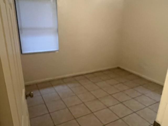 unfurnished room featuring light tile patterned floors and baseboards