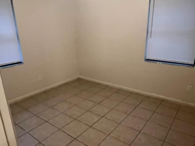 empty room with baseboards and light tile patterned flooring