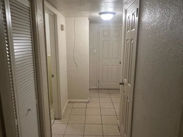 hallway with light tile patterned flooring and baseboards