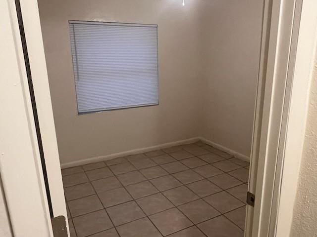 tiled empty room featuring baseboards