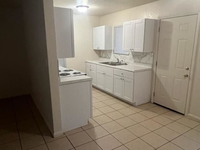 kitchen featuring tasteful backsplash, white cabinets, a sink, light countertops, and light tile patterned flooring