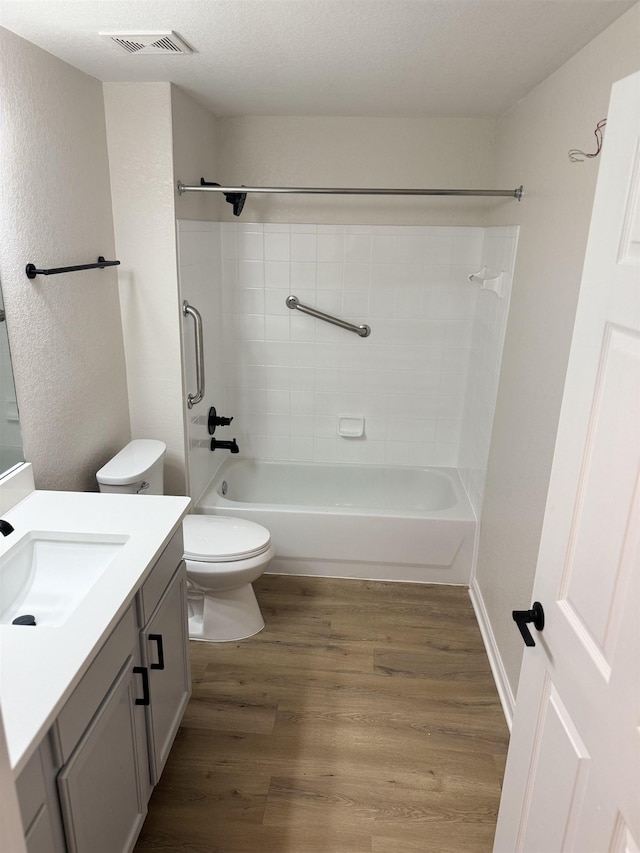 full bathroom featuring tub / shower combination, hardwood / wood-style floors, a textured ceiling, toilet, and vanity