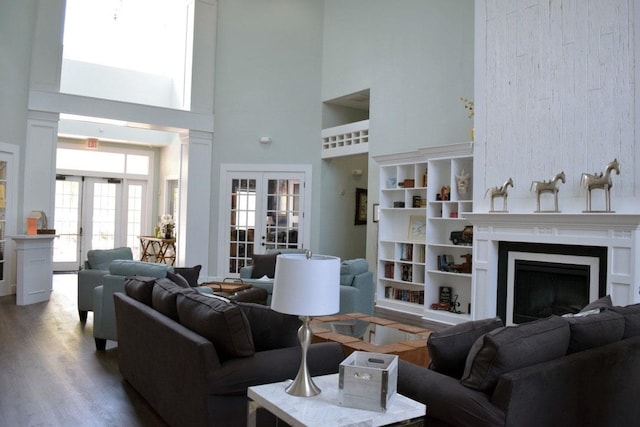 living room featuring wood-type flooring, a towering ceiling, and french doors