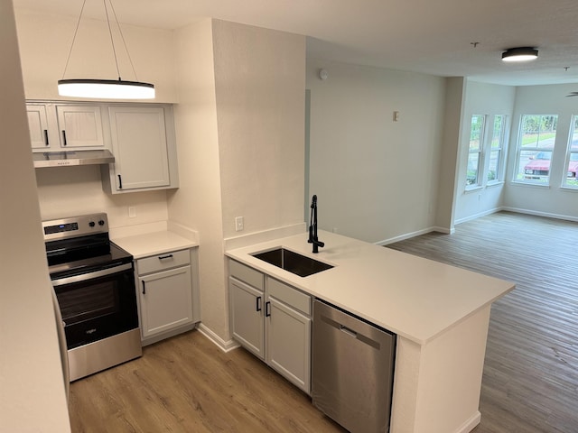 kitchen with kitchen peninsula, sink, stainless steel appliances, and light hardwood / wood-style floors