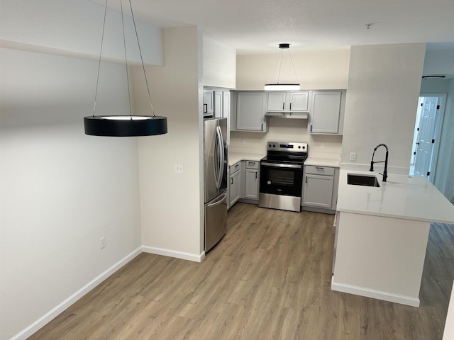 kitchen featuring sink, kitchen peninsula, decorative light fixtures, gray cabinets, and appliances with stainless steel finishes