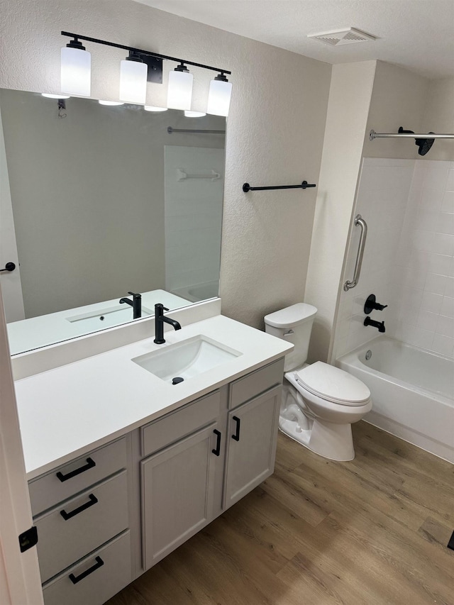 full bathroom with vanity, a textured ceiling, wood-type flooring, washtub / shower combination, and toilet