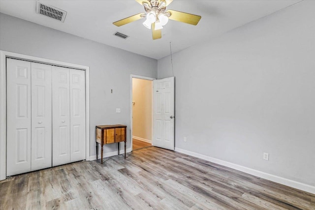 unfurnished bedroom featuring ceiling fan, light hardwood / wood-style floors, and a closet