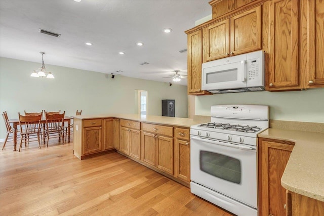 kitchen featuring white appliances, ceiling fan with notable chandelier, decorative light fixtures, kitchen peninsula, and light wood-type flooring