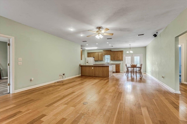 kitchen with pendant lighting, ceiling fan, light hardwood / wood-style floors, white fridge with ice dispenser, and kitchen peninsula