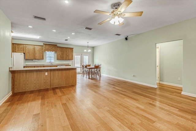 kitchen with sink, light hardwood / wood-style flooring, ceiling fan, kitchen peninsula, and white fridge