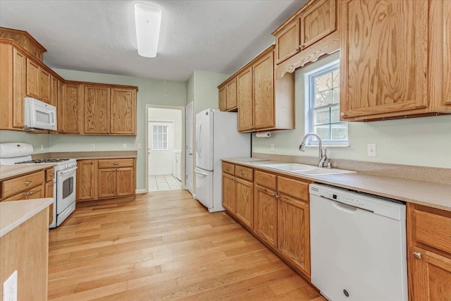 kitchen featuring white appliances, sink, and light wood-type flooring