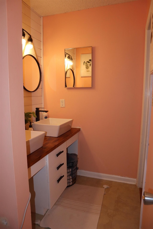 bathroom with tile patterned flooring, vanity, and a textured ceiling