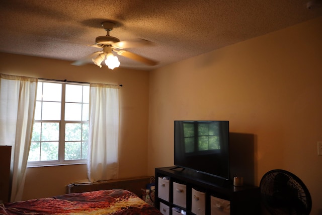 bedroom with ceiling fan and a textured ceiling