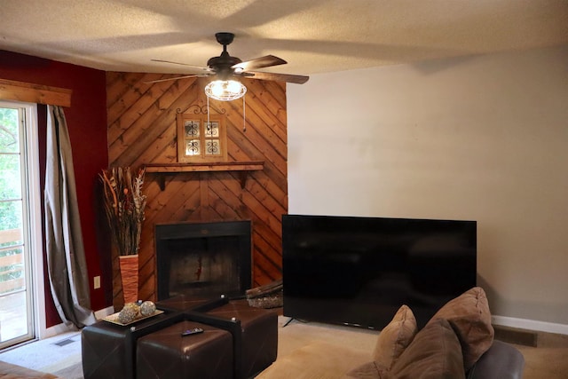 living room with wooden walls, ceiling fan, light colored carpet, and a textured ceiling