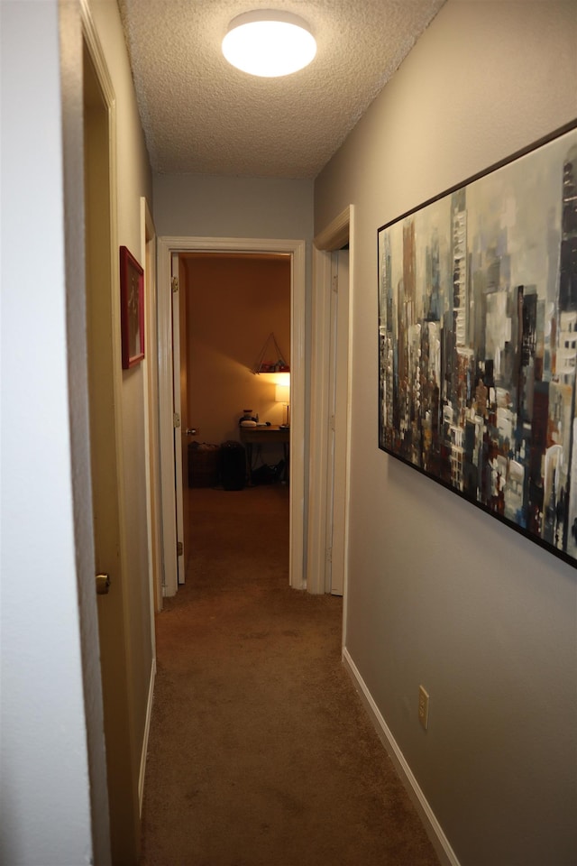 hallway featuring carpet flooring and a textured ceiling