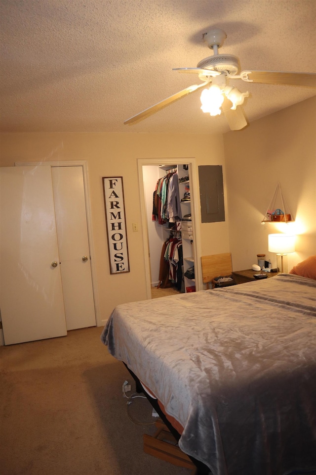 carpeted bedroom with ceiling fan, a textured ceiling, electric panel, and a closet