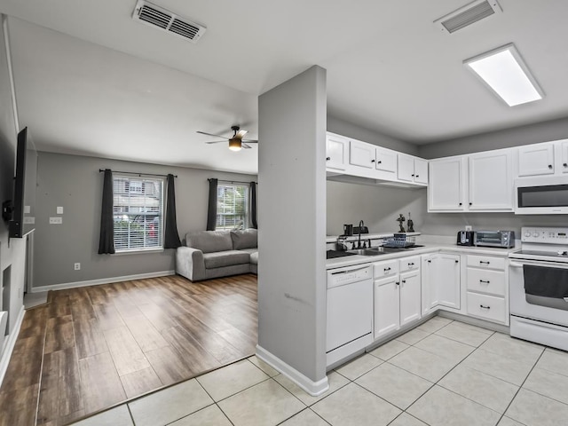 kitchen featuring white appliances, white cabinets, sink, and light tile patterned floors