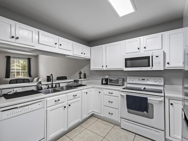 kitchen featuring white appliances, white cabinetry, light tile patterned floors, and sink