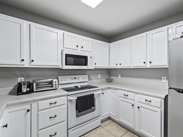 kitchen with white appliances, white cabinets, and light tile patterned flooring