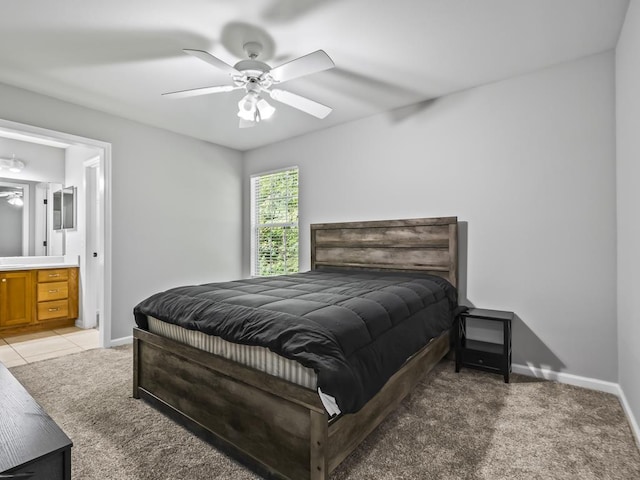 bedroom featuring ceiling fan, light colored carpet, and ensuite bath